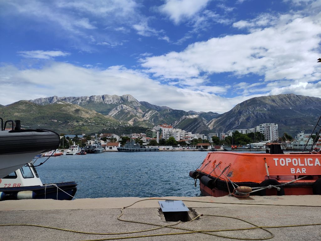 Blick von der Zollpier in Bar auf die Berge, im Vordergrund rechts einer der lokalen Schlepper und links ein Polizeiboot